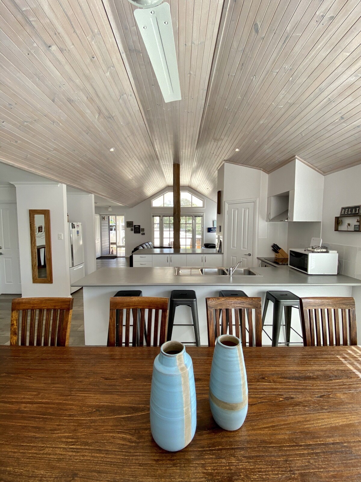 Brumby Cottage kitchen with white cabinets, timber beams, fridge, microwave, oven and gas cooktop, window to verandah, Margaret River