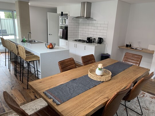 Brumby Cottage kitchen with white cabinets, timber beams, fridge, microwave, oven and gas cooktop, window to verandah, Margaret River