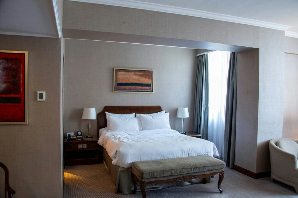 Simple motel room with neatly made bed and bedside lamp