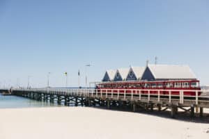 The historic Busselton Jetty stretching into turquoise water under clear blue skies.