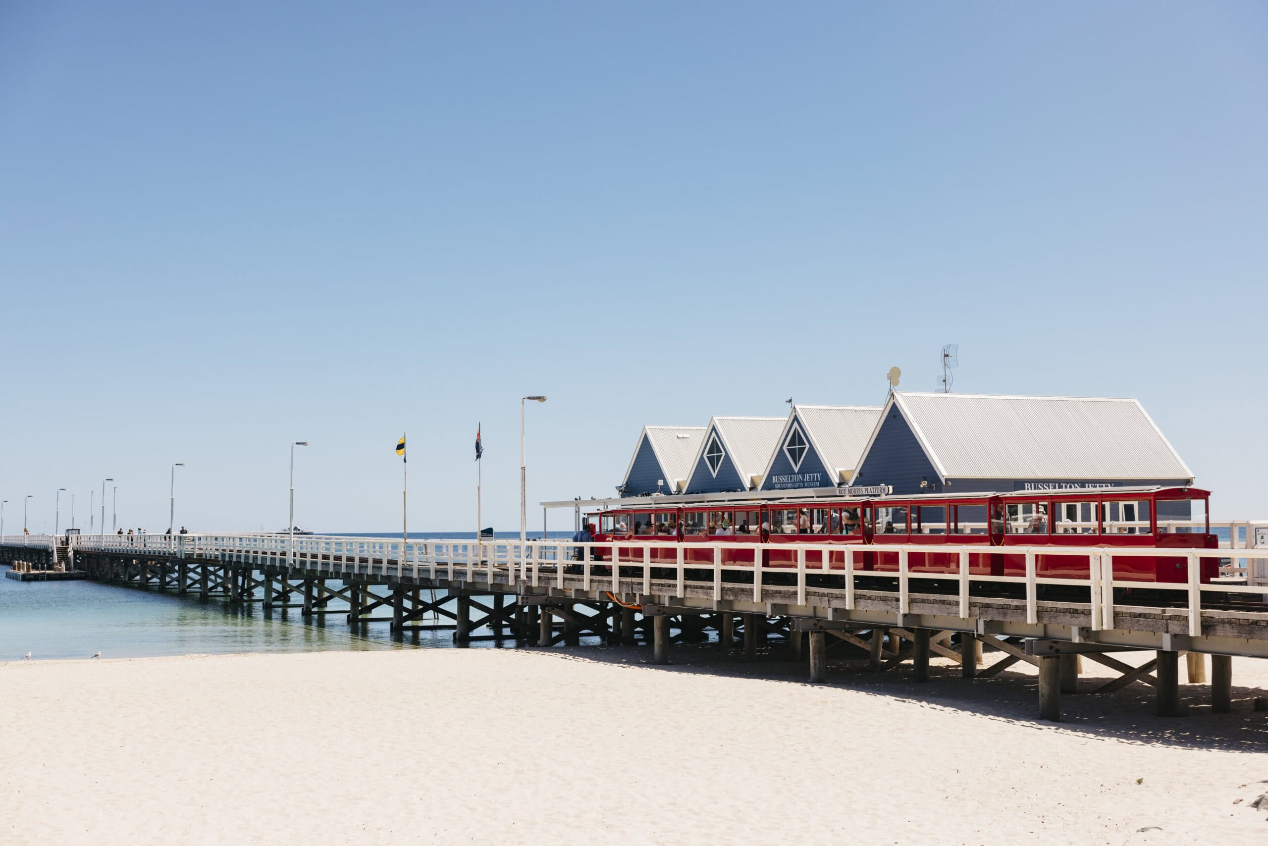 The historic Busselton Jetty stretching into turquoise water under clear blue skies.